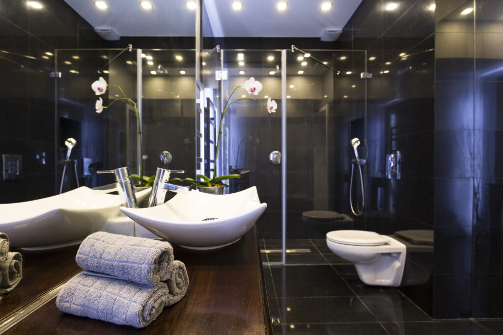 Modern bathroom with walk-in glass shower, double sink vanity, and marble tiles